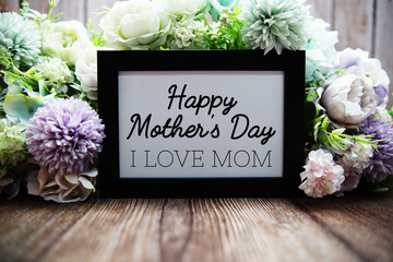 Happy Mother's Day text with flower decoration on wooden background