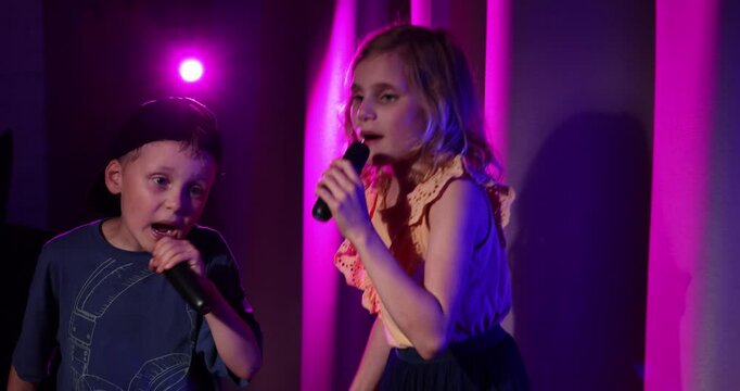 boy and girl sing in microphones and dance joyfully at home. karaoke party