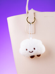 Close-up of a plush bag charm featuring a funny white cloud on blue bag