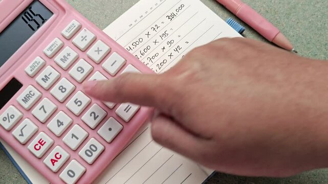 Calculating Finances: Pink Calculator, Notebook, and Hand in Action, Financial Planning