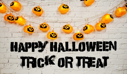 Happy Halloween Trick or Treat text with LED pumpkin decoration on white brick wall background