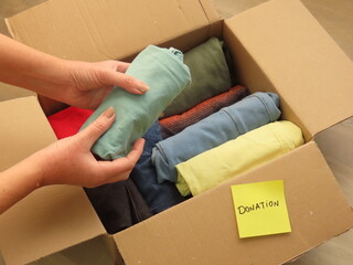 Woman hands preparing a box of clothes for donation. Packing clothes for donation.