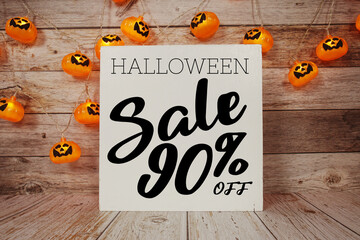Halloween Sale 90% off text with LED pumpkin decoration on wooden background
