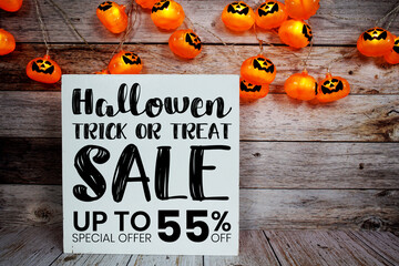 Halloween Sale 55% off text with LED pumpkin decoration on wooden background