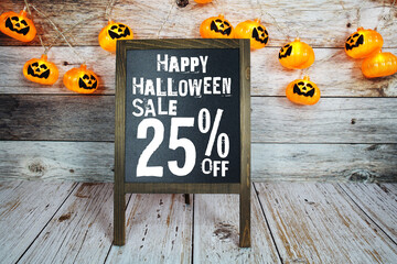 Halloween Sale 25% off text with LED pumpkin decoration on wooden background