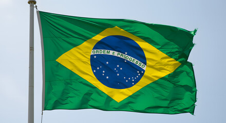 Brazilian Flag Flutters in the Wind Over a Lush Green Landscape, Symbol of National Pride and Unity