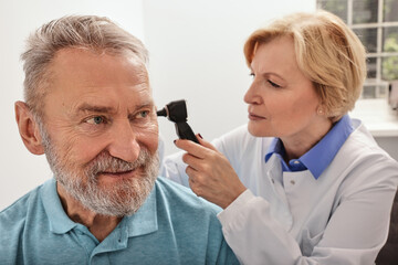 Hearing test for mature people, otoscopy. Otolaryngologist doctor checking senior man's ear using...