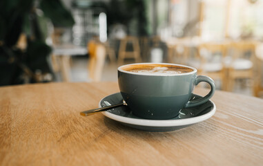 Hot coffee in a cafe with morning sunlight,coffee latte art on wood table
