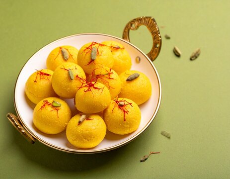 Classic kesar peda with cardamom garnish on olive green background &mdash; traditional Indian milk sweet