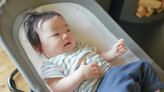 Baby sleeping in a bouncer cradle inside a house