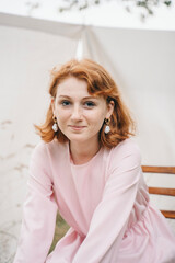 Smiling young woman in pink dress with pearl earrings