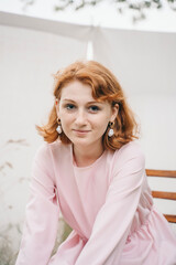 Smiling young woman in pink dress with pearl earrings