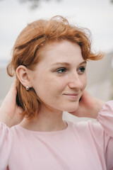 Naklejka premium Smiling red-haired woman in soft pink dress, close-up