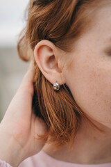 Close-up of a woman's ear with minimalist silver earring