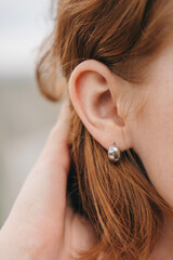 Close-up of a woman's ear with minimalist silver earring