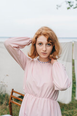 Fototapeta premium Young redhead woman in pink dress with blue beaded necklace