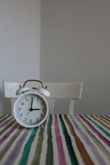 White table bell alarm clock on a colored striped base