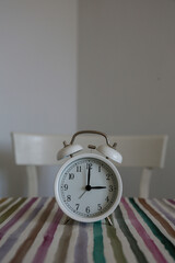 White table bell alarm clock on a colored striped base