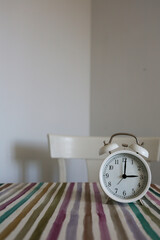 White table bell alarm clock on a colored striped base