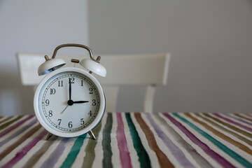 White table bell alarm clock on a colored striped base