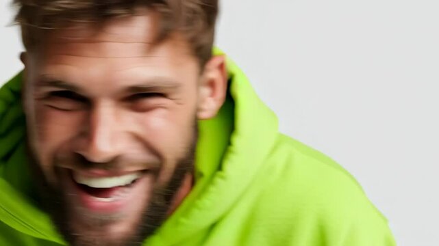 Young man with tousled hair expressing joy in vibrant green hoodie in a studio setting