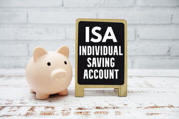 ISA Individual Saving Account text with piggy bank on wooden background
