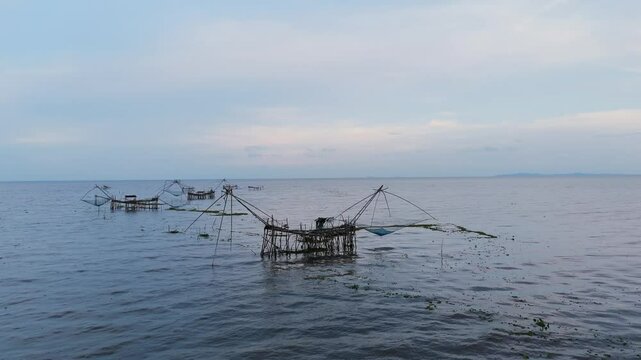 Traditional bamboo fishing nets in a calm lake at dusk. Peaceful rural scene capturing local fishing lifestyle in Southeast Asia. Ideal for travel, nature, and cultural content.