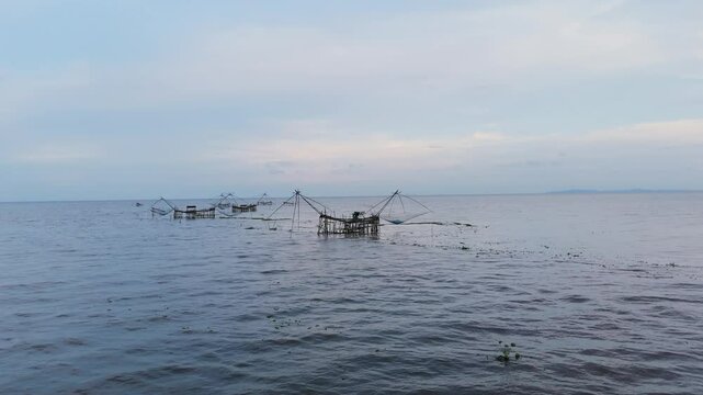 Traditional bamboo fishing nets in a calm lake at dusk. Peaceful rural scene capturing local fishing lifestyle in Southeast Asia. Ideal for travel, nature, and cultural content.
