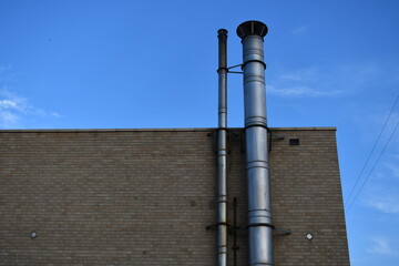 Exhaust pipes attached to side of brick building.