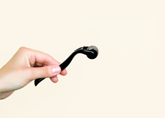 Person holding a black dermaroller against a neutral background