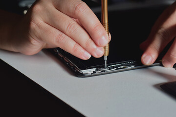 Computer repair technician, laptop motherboard repair technician uses a screwdriver to disassemble computer components to remove them for replacement and repair.