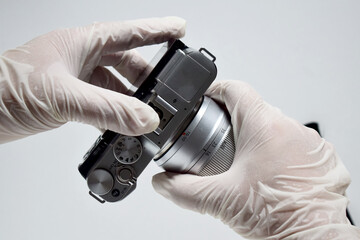 A camera repairman is manually removing the lens from the camera.