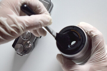 A camera repairman is cleaning the sensor and lens with a brush.