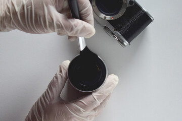 A camera repairman is cleaning the sensor and lens with a brush.