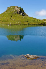 Reflections on blue waters of Lac Claret in Belledonne mountain range