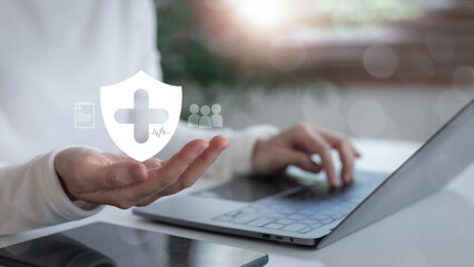 Businesswoman using laptop with healthcare shield icon representing digital health protection,...