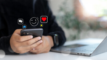 User holding smartphone with social media reactions, emoji icons, likes, and comments. Concept of digital communication, online interaction, and social engagement.