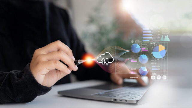 Hand pointing to cloud computing icon with data flow and analytics charts on a laptop. Concept of big data processing, cloud storage, and business intelligence technology.