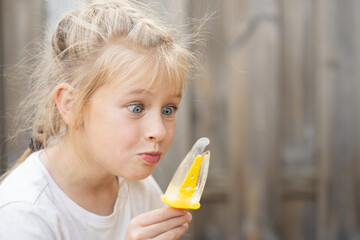 A happy little girl enjoys a frozen ice pop on a sunny day, embodying carefree childhood and summer vacation bliss. Perfect for family lifestyle content and food advertising.