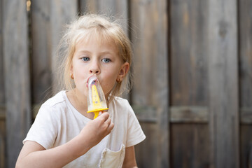 A young girl experiences the simple pleasure of a melting ice pop on a hot summer afternoon. Ideal for promoting summer products and happy family moments.
