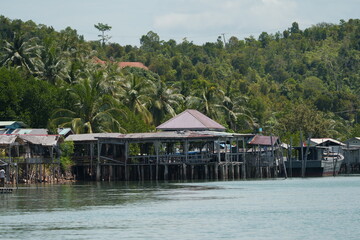 Tranquil Stilt Village Above Water Framed by Palms and Hills