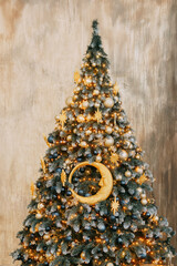 Decorated Christmas tree with shiny golden and blue ornaments, bright lights, and gifts below. Holiday season interior decor with cozy sofa.