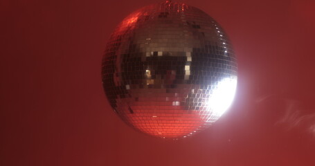Close-up footage of a spinning disco ball reflecting colorful lights in all directions against a...