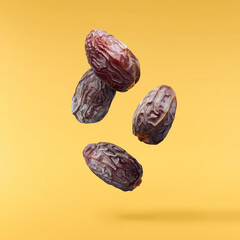 Dried sweet Date fruit falling in the air isolared on yellow background