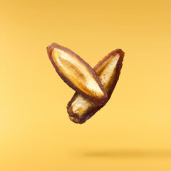 Dried sweet Date fruit falling in the air isolared on yellow background