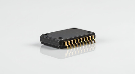 A small black electronic chip with exposed gold pins, precisely isolated on a clean white background, representing microtechnology and hardware.
