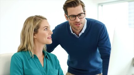 In a bright office, a man and woman engage in a productive discussion, sharing insights while looking at a computer screen. Their teamwork highlights a collaborative atmosphere