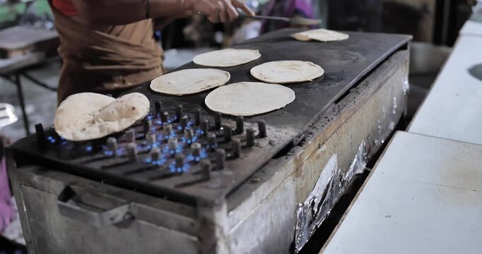 Indian caterers making fresh chapatis and serving them hot in a buffet setup during a festive event