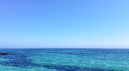 Obraz premium Clear Blue Sea and Sky with Rocky Coastline