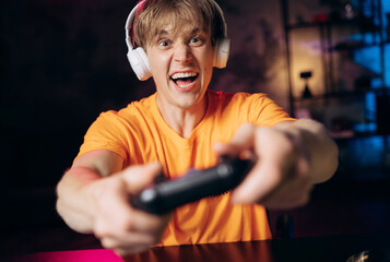 Happy gamer celebrating a win, smiling and holding a controller enthusiastically. Positive emotions...